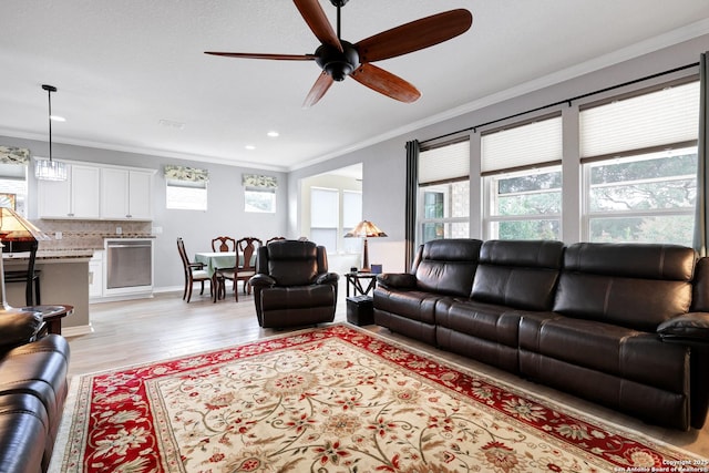 living room with ornamental molding, recessed lighting, ceiling fan, and light wood-style flooring