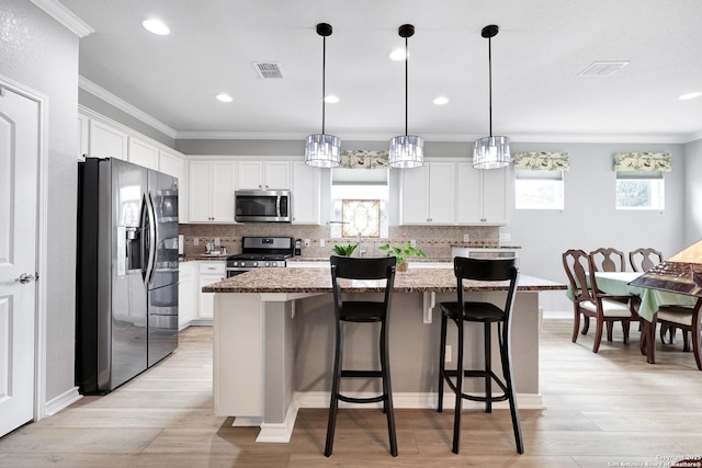 kitchen featuring appliances with stainless steel finishes, visible vents, ornamental molding, and a kitchen island