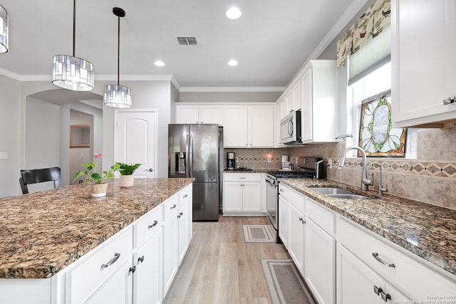 kitchen featuring a kitchen island, a sink, visible vents, light wood-style floors, and appliances with stainless steel finishes