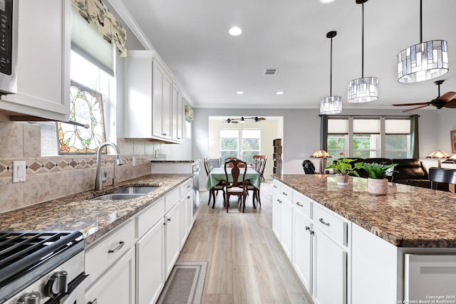 kitchen featuring backsplash, ornamental molding, light wood-style floors, a sink, and ceiling fan