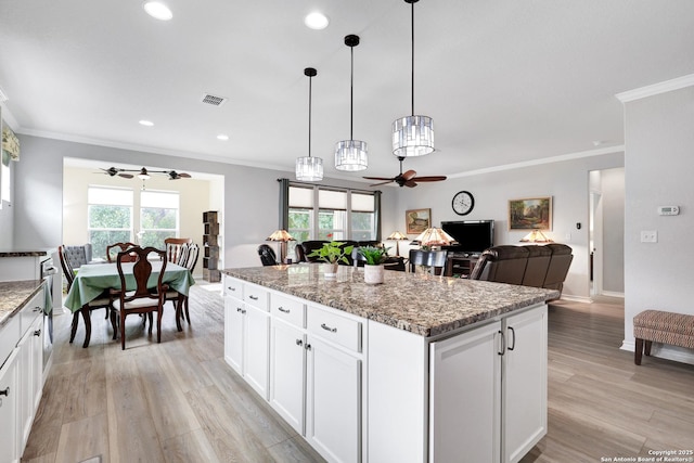 kitchen with ornamental molding, a center island, visible vents, and light wood finished floors