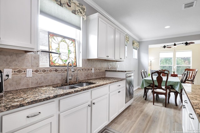 kitchen featuring dark stone counters, ornamental molding, a sink, white cabinetry, and stainless steel dishwasher