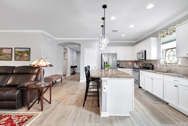 kitchen featuring arched walkways, stainless steel appliances, visible vents, open floor plan, and a sink