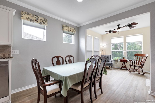 dining room with ornamental molding, a healthy amount of sunlight, light wood-style flooring, and baseboards