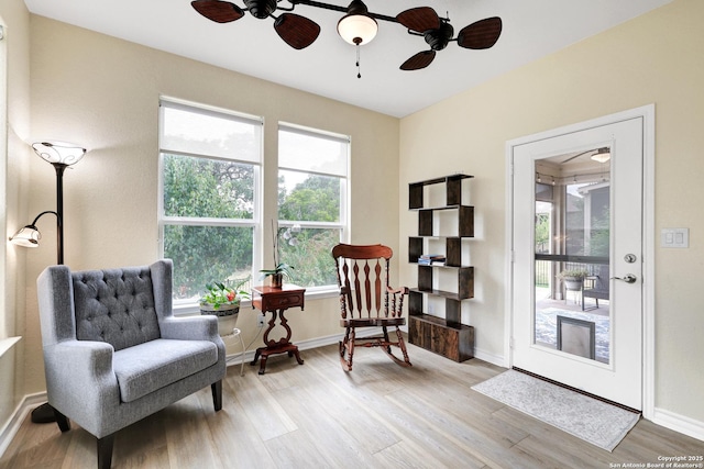 sitting room featuring a ceiling fan, light wood-type flooring, and baseboards