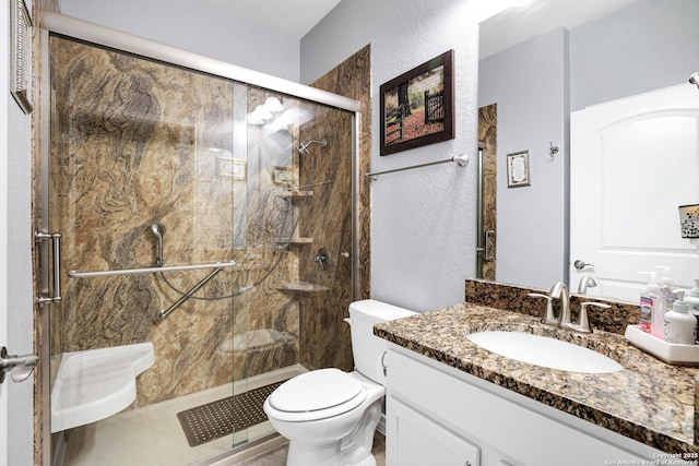 full bath with a marble finish shower, a textured wall, vanity, and toilet