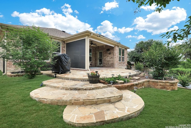 back of property with a yard, a patio, and brick siding