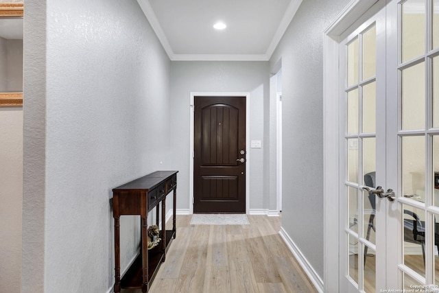 entryway featuring a textured wall, wood finished floors, baseboards, ornamental molding, and french doors