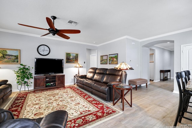 living room with arched walkways, light wood-style floors, visible vents, and baseboards