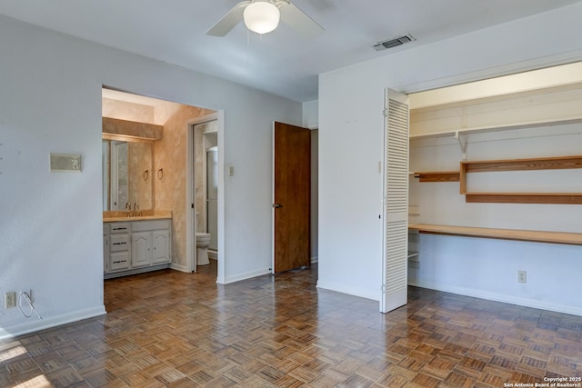 unfurnished bedroom featuring a closet, ensuite bathroom, sink, and dark parquet floors