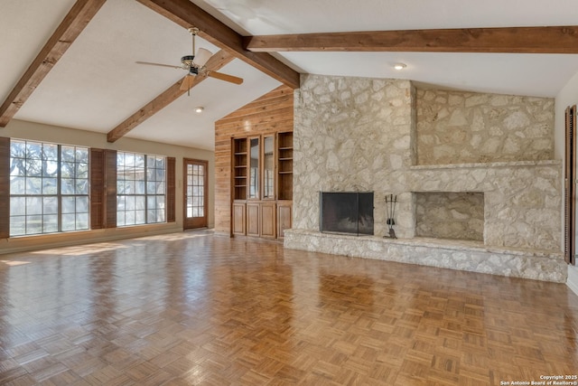 unfurnished living room featuring parquet flooring, a stone fireplace, high vaulted ceiling, ceiling fan, and beam ceiling