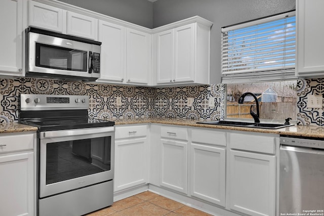 kitchen with white cabinetry, appliances with stainless steel finishes, sink, and light tile patterned flooring