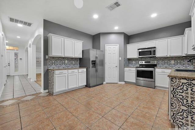 kitchen featuring appliances with stainless steel finishes, tasteful backsplash, sink, white cabinets, and light tile patterned floors