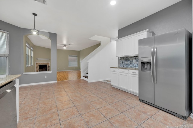 kitchen with light stone countertops, light tile patterned floors, stainless steel appliances, and white cabinets