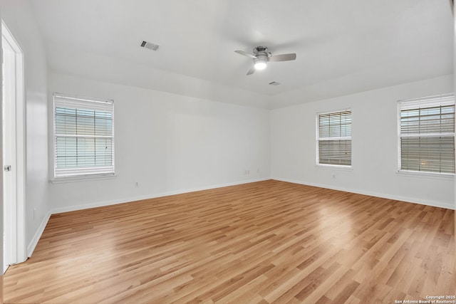 spare room with ceiling fan, a wealth of natural light, and light hardwood / wood-style floors