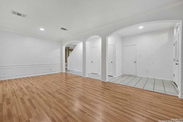 empty room with ornamental molding and light hardwood / wood-style floors