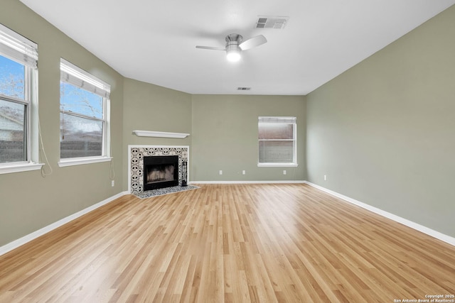 unfurnished living room with ceiling fan, light hardwood / wood-style floors, and a tile fireplace