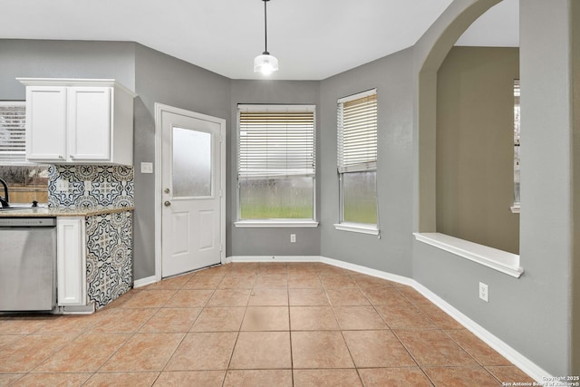 kitchen with decorative light fixtures, light tile patterned floors, dishwasher, white cabinets, and backsplash