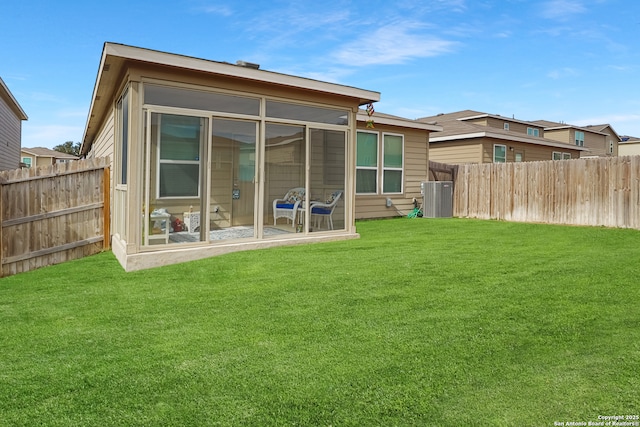 back of house featuring cooling unit, a sunroom, and a lawn