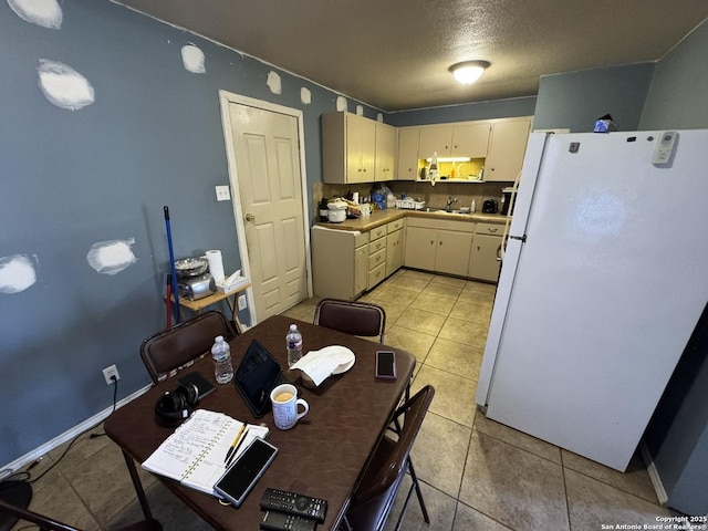 kitchen featuring light tile patterned floors, sink, white refrigerator, a textured ceiling, and cream cabinetry