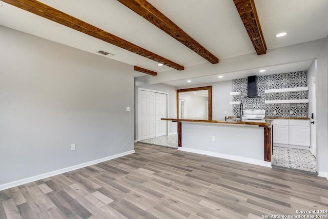 unfurnished living room featuring beam ceiling and light hardwood / wood-style flooring