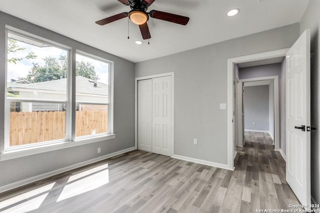 unfurnished bedroom featuring ceiling fan, light hardwood / wood-style floors, and a closet