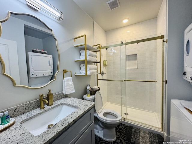 bathroom featuring stacked washer / dryer, vanity, an enclosed shower, and toilet