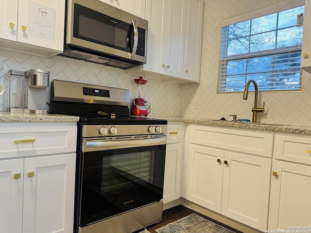 kitchen featuring white cabinetry, light stone counters, and stainless steel appliances