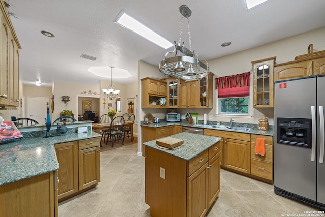 kitchen featuring pendant lighting, sink, appliances with stainless steel finishes, a center island, and light stone countertops