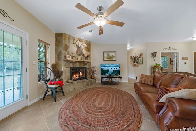 living room featuring light tile patterned flooring, ceiling fan, a fireplace, and a wealth of natural light