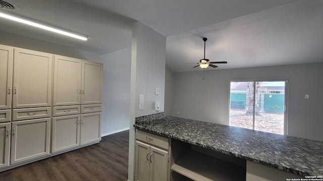 kitchen featuring built in desk, lofted ceiling, dark stone counters, ceiling fan, and dark wood-type flooring