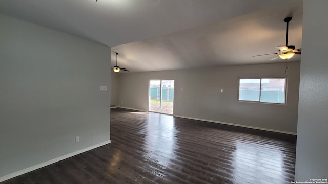 unfurnished room featuring lofted ceiling, dark wood-type flooring, a wealth of natural light, and ceiling fan