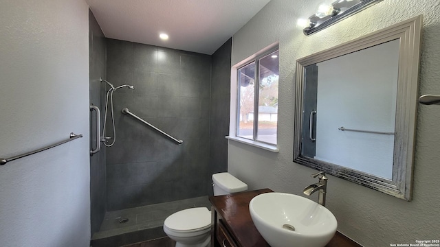 bathroom featuring vanity, toilet, and a tile shower