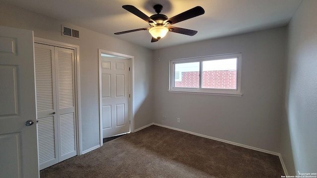 unfurnished bedroom with dark colored carpet, ceiling fan, and a closet