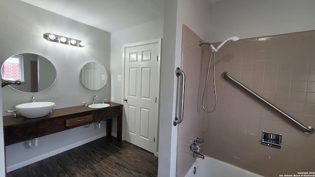 bathroom featuring wood-type flooring, tiled shower / bath combo, and vanity