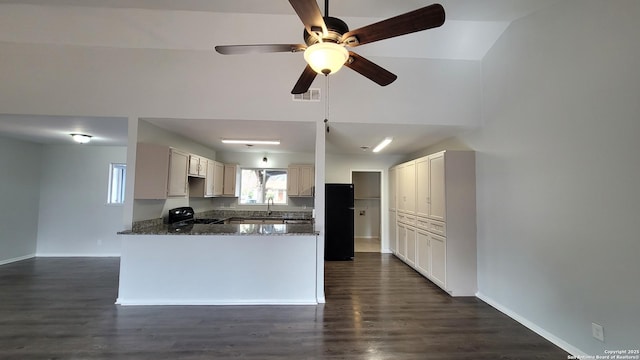 kitchen with black appliances, dark stone countertops, dark hardwood / wood-style flooring, and kitchen peninsula