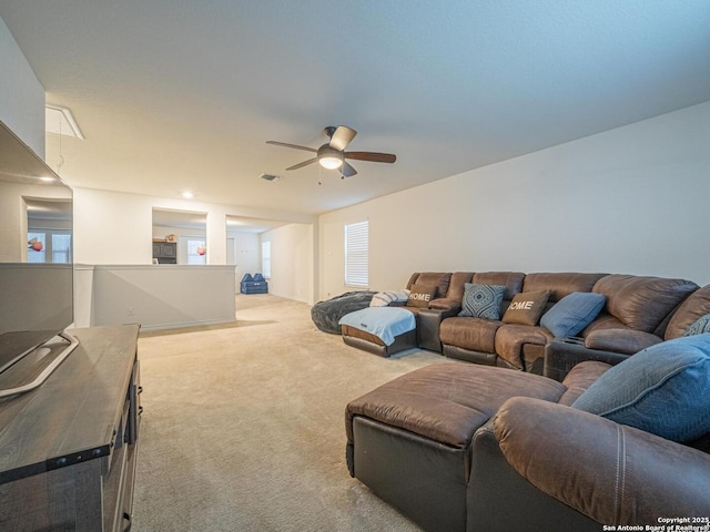 living room featuring light carpet, a healthy amount of sunlight, and ceiling fan