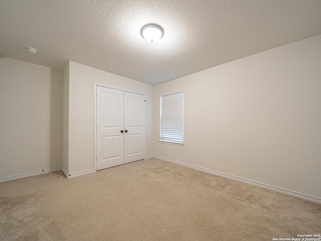 unfurnished bedroom with a closet, light carpet, and a textured ceiling