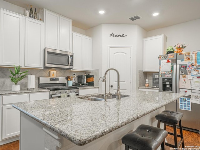 kitchen with a kitchen island with sink, white cabinetry, and appliances with stainless steel finishes