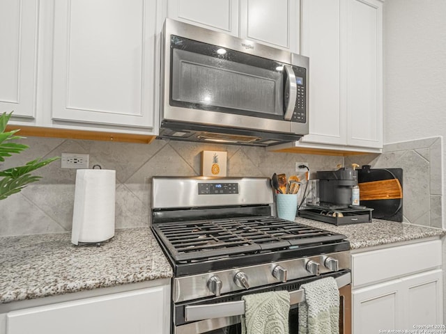 kitchen featuring white cabinetry, light stone countertops, tasteful backsplash, and stainless steel appliances