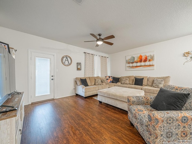 living room featuring dark wood-type flooring, ceiling fan, and a textured ceiling