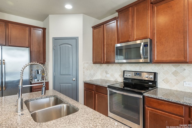 kitchen featuring light stone countertops, appliances with stainless steel finishes, sink, and decorative backsplash