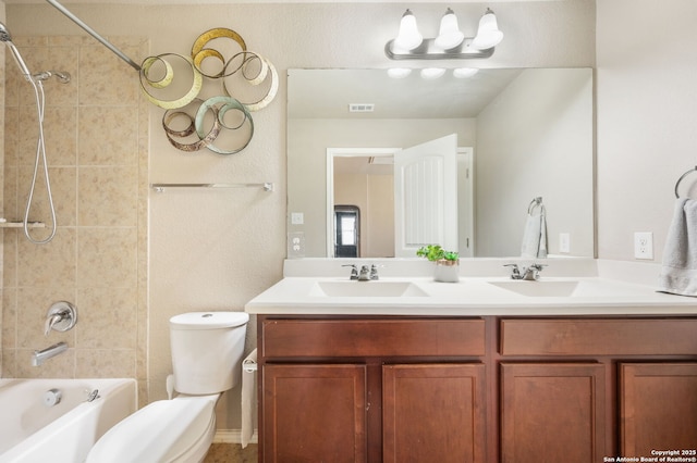 full bathroom featuring vanity, tiled shower / bath, and toilet