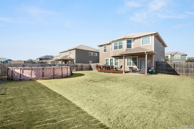 rear view of property with a yard and a swimming pool side deck