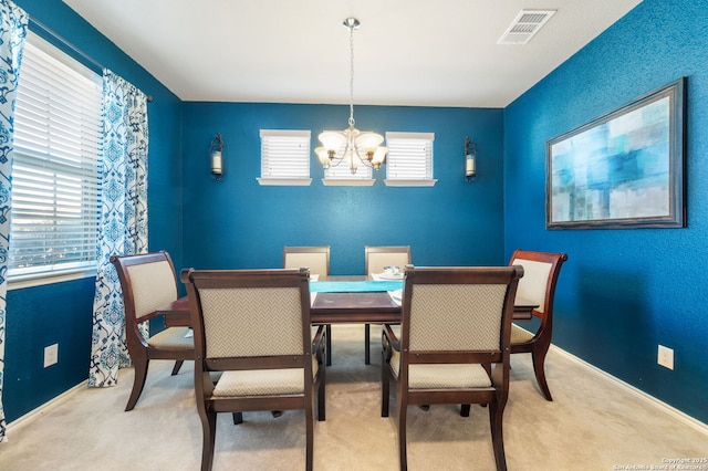 dining area with light carpet and a chandelier