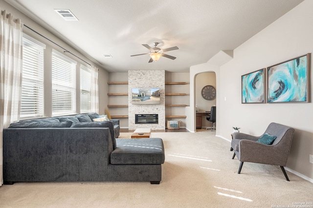 living room with ceiling fan, light carpet, built in features, and a fireplace