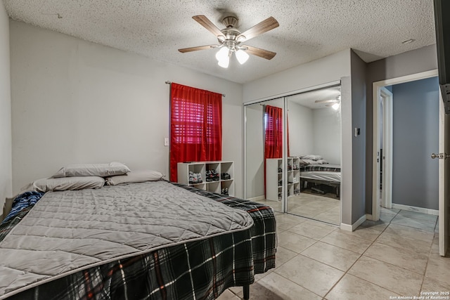 tiled bedroom with ceiling fan, a textured ceiling, and a closet