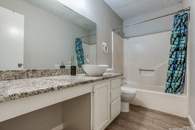 full bathroom with shower / bath combo, vanity, a textured ceiling, and toilet