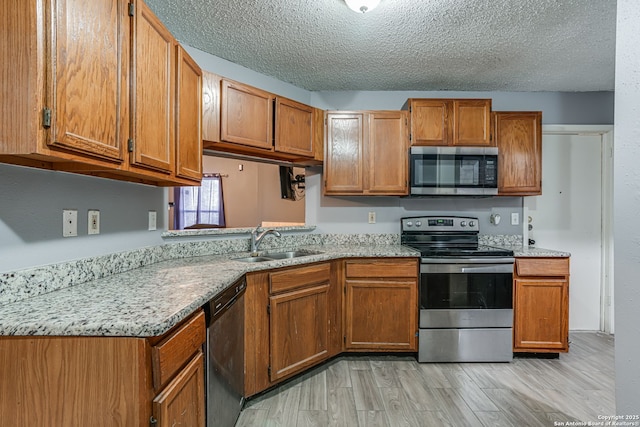 kitchen with sink, light wood-type flooring, a textured ceiling, and appliances with stainless steel finishes