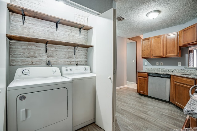 laundry room featuring sink, washer and dryer, a textured ceiling, and light wood-type flooring